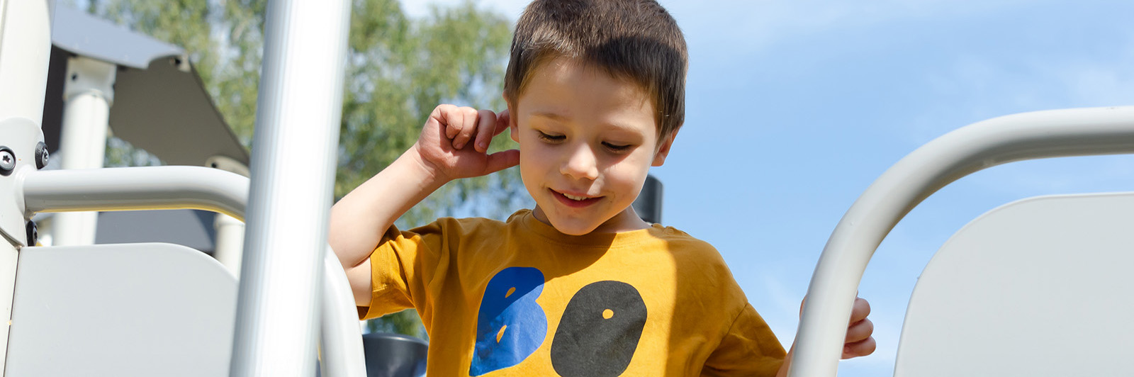 Boy on top of a large playground unit.